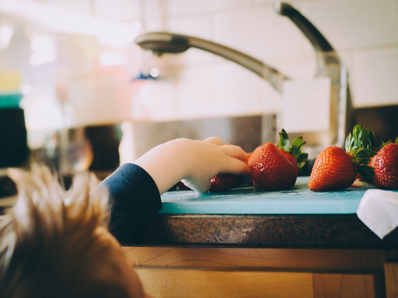 Rørleggerkjeden VB barn strekker seg etter jordbær på kjøkkenbenken